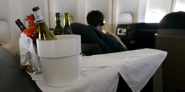 With bottles of wine in the foreground, a passenger watches a movie inside the first class cabin of a commercial passenger 747-400 airplane. (Photo by Brooks Kraft LLC/Corbis via Getty Images)