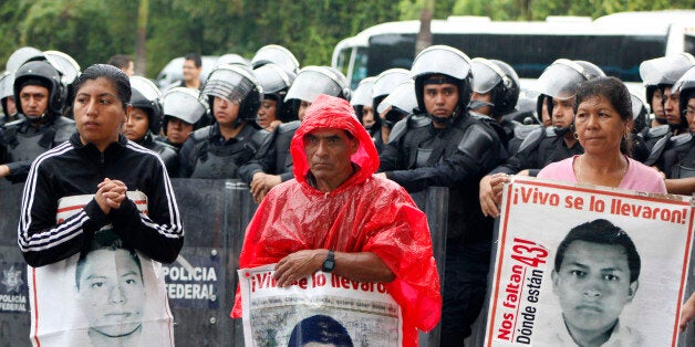 Relatives of the 43 missing students of Ayotzinapa hold their portraits in front of riot police during a protest outside the hotel where the 47th OAS General Assembly takes place in Cancun, Mexico on June 19, 2017. The students, from a rural teachers college in the southern state of Guerrero, disappeared after they were attacked by local police in Iguala on September 26, 2014. / AFP PHOTO / Gonzalo ZAPATA (Photo credit should read GONZALO ZAPATA/AFP/Getty Images)