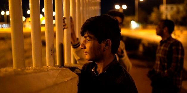An Afghan migrant looks through fence at the western port of Patras, waiting for the opportunity to jump over a fence into a ferry terminal in Patras on June 20, 2017.Khalid, a 13-year-old from Afghanistan, spends his days in squalor repeatedly trying to scale a metal fence separating him from the better life he dreams about at night. / AFP PHOTO / Angelos Tzortzinis (Photo credit should read ANGELOS TZORTZINIS/AFP/Getty Images)