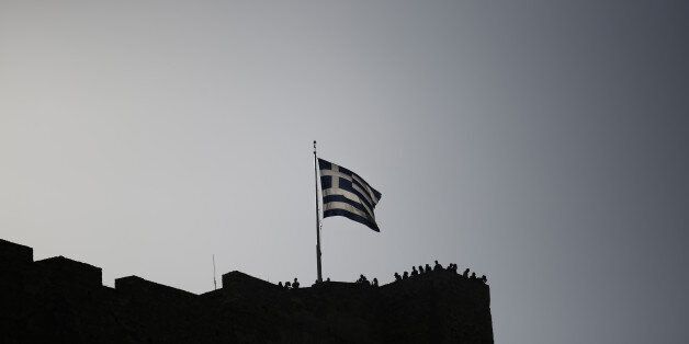 A Greek national flag flies from the top of the Acropolis hill above visiting tourists in Athens, Greece, on Wednesday, June 28, 2017. The change in sentiment toward Greece -- the epicenter of the European financial crisis -- is reflected in the fact that countrys bond yields are the lowest since before the turmoil even as the debt remains deep in junk territory. Photographer: Kostas Tsironis/Bloomberg via Getty Images