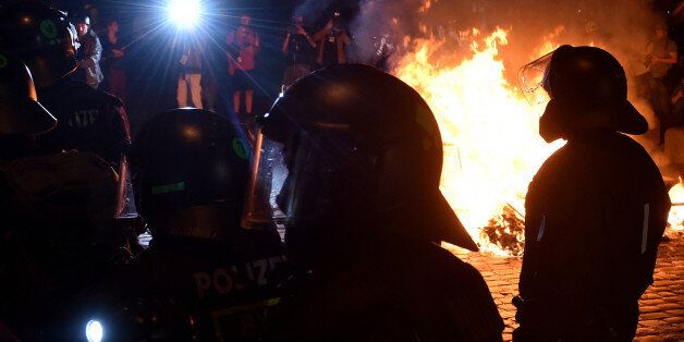 Police officers walk in front of a fire after the 'Welcome to Hell' rally against the G20 summit in Hamburg, northern Germany on July 6, 2017. Leaders of the world's top economies will gather from July 7 to 8, 2017 in Germany for likely the stormiest G20 summit in years, with disagreements ranging from wars to climate change and global trade. / AFP PHOTO / Christof STACHE (Photo credit should read CHRISTOF STACHE/AFP/Getty Images)
