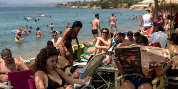 People sunbathe and relax by a beach south of Athens on June 25, 2017 as temperatures reached 35 degrees Celsius. / AFP PHOTO / Eleftherios Elis (Photo credit should read ELEFTHERIOS ELIS/AFP/Getty Images)