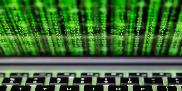 Laptop screen and keyboard with green binary matrix code closeup cybersecurity concept