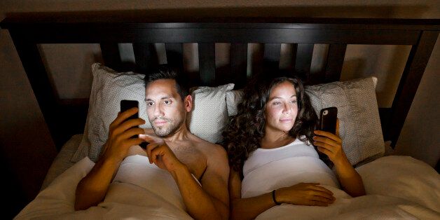 Young couple on their phones in bed.
