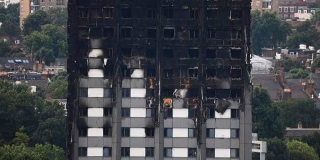Unburned lower floors with untouched cladding in place are seen with the burnt out upper floors of the Grenfell Tower block in North Kensington, west London, on June 18, 2017. The presumed death toll from the London tower block inferno jumped to 58 on Saturday as embattled Prime Minister Theresa May, accused of misreading the growing anger over the tragedy, pledged action after meeting survivors desperately seeking answers. / AFP PHOTO / Tolga AKMEN (Photo credit should read TOLGA AKMEN/A
