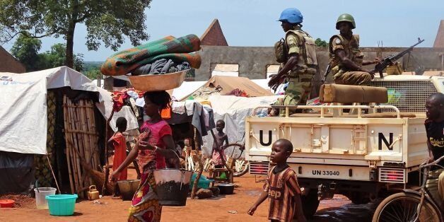 A woman and a child walk past UN peacekeepers from Gabon patrolling the Central African Republic town of Bria on June 12, 2017.After a renewed flare of violence in the region of Bria, the UN called the Central Africans to find a political solution and international donors to 'keep their promises' of aid. / AFP PHOTO / SABER JENDOUBI (Photo credit should read SABER JENDOUBI/AFP/Getty Images)