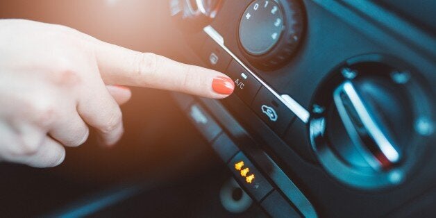 Woman turns on air conditioning in her car. Modern car interior