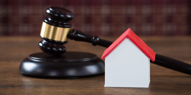 Closeup of wooden mallet with house model on table in courtroom