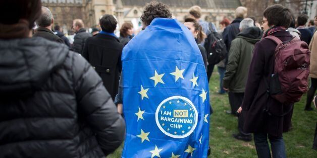 A man wears a sign that reads 'I am NOT a bargaining chip'on a European Union flag during a 'Flag Mob' demonstration in Parliament Square in central London on February 20, 2017, part of a national day of action in support of migrants in the UK. Under the banner One Day Without Us men, women and children come together for a day of action to stress that they want Britain to remain open and welcoming. A number of businesses closed for the day to make the point that the Britain couldnt manage for even one day without the contribution of migrants. / AFP / Justin TALLIS (Photo credit should read JUSTIN TALLIS/AFP/Getty Images)