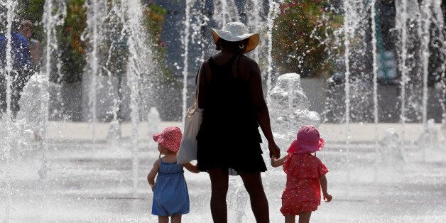 A woman with children cool off in water fountains in a park as hot summer temperatures hit Paris, France, June 22, 2017. REUTERS/Jean-Paul Pelissier