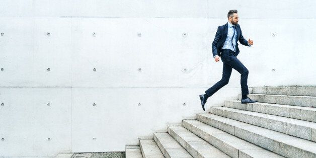 Young businessman running on stairs in the street