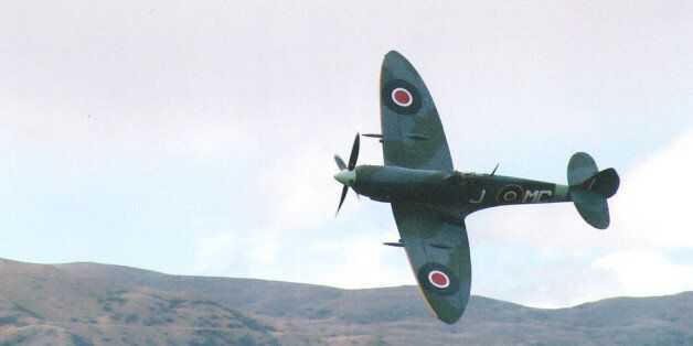 A spitfire flies low over airfield, banking towards the camera