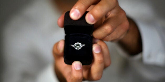 A man proposing and holding up an engagement ring