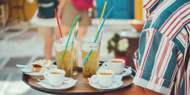 Waiter holding try with some drinks, coffees and Greek yoghourt at the terrace bar.