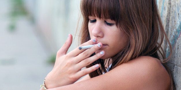 Teenage girl smoking cigarette in urban environment.
