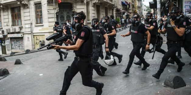 Turkish anti riot police officers fire rubber bullets to disperse demonstrators gathered for a rally staged by the LGBT community on Istiklal avenue in Istanbul on June 26, 2016.Riot police fired tear gas and rubber bullets to disperse protesters defying a ban on the city's Gay Pride parade. Authorities in Turkey's biggest city had banned the annual parade earlier this month citing security reasons, sparking anger from gay rights activists. / AFP / OZAN KOSE (Photo credit should read OZAN