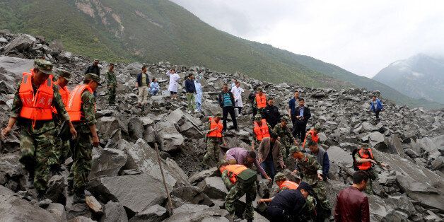 In this picture taken on June 24, 2017, rescue workers search for survivors at the site of a landslide in in Xinmo village, Diexi town of Maoxian county, Sichuan province.Rescuers dug through earth and rocks for a second day on Sunday in an increasingly bleak search for some 118 people still missing after their village in southwest China was buried by a huge landslide. Rescuers have pulled 15 bodies from the avalanche of rocks that crashed into 62 homes in Xinmo, a once picturesque mountain village nestled by a river in Sichuan province. / AFP PHOTO / STR / China OUT (Photo credit should read STR/AFP/Getty Images)