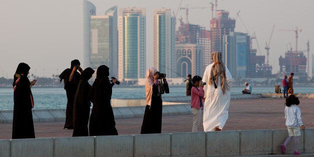 DOHA, QATAR - DECEMBER 21: New high-rise office buildings and hotels, some of them still under construction, stand in the West Bay and Oneiza district near City Center mall and build the skyline at the opposite of the promenade at the Al Corniche road are photographed by Qatari people in their traditional clothes called dishdasha (man) and abaya (woman) on December 21, 2011 in Doha, Qatar. The FIFA World Cup 2022 will take place in Qatar. (Photo by Nadine Rupp/Getty Images)