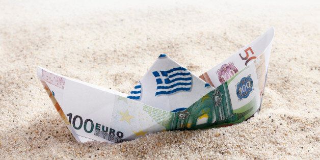 Origami paper boat of euro notes on sand