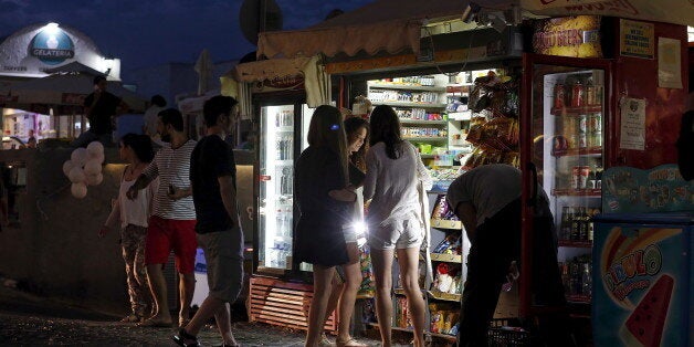 Tourists buy water from a vendor on the Greek island of Santorini, Greece, July 1, 2015. Greece's last-minute overtures to international creditors for financial aid on Tuesday were not enough to save the country from becoming the first developed economy to default on a loan with the International Monetary Fund. REUTERS/Cathal McNaughton