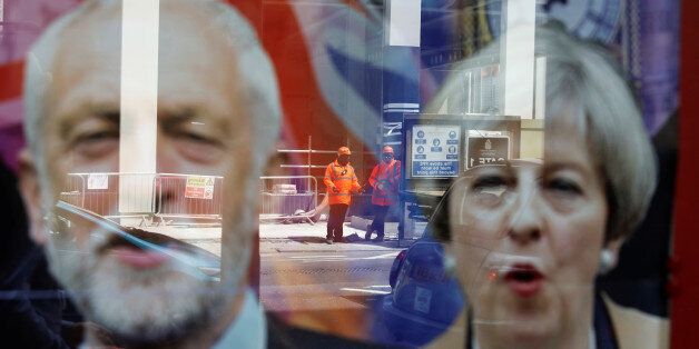Workers in protective equipment are reflected in the window of a betting shop with a display inviting customers to place bets on tbe result of the general election with images of Britain's Prime Minister Theresa May and opposition Labour Party leader Jeremy Corbyn, in London, June 7, 2017. REUTERS/Marko Djurica TPX IMAGES OF THE DAY