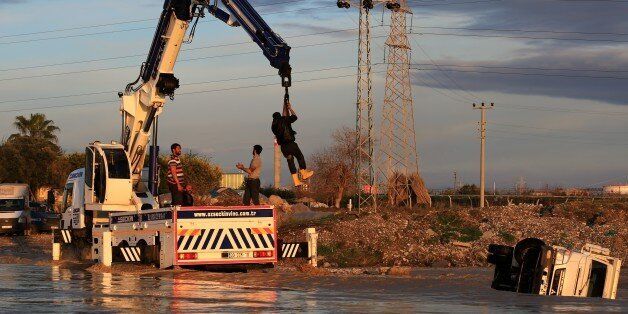 MERSIN, TURKEY - MARCH 03: A man is rescued with the help of a crane after a pick-up truck toppled over in a stream bed in Mersin, Turkey on March 3, 2017. A pick-up truck, which was carrying the people who tried to cross the stream bed after the flow rate of the stream bed increased due to rainfall, toppled over in Turkey's Mersin. Two people, who managed to climb over the pick-up truck at the last moment, have been rescued with the help of a crane. (Photo by Mustafa Gungor/Anadolu Agency/Gett