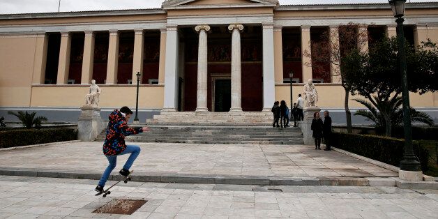 A youth performs stunts with his skateboard as a Greek national flag flutters atop the Athens' University February 14, 2015. REUTERS/Alkis Konstantinidis (GREECE - Tags: SOCIETY)