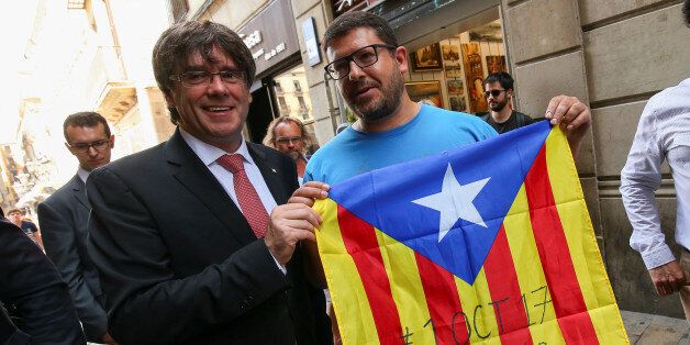 Catalonia's regional President Carles Puigdemont poses next to a pro-independence supporter with a Catalan Estelada flag showing the date for which the regional government called for a referendum on a split from Spain outside the Palau de la Generalitat, the regional government headquarters, in Barcelona, Spain, June 9, 2017. The flag reads