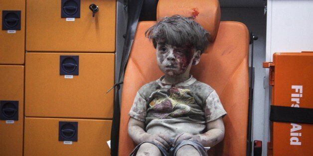 ALEPPO, SYRIA - AUGUST 17 : 5-year-old wounded Syrian kid Omran Daqneesh sits alone in the back of the ambulance after he got injured during Russian or Assad regime forces air strike targeting the Qaterji neighbourhood of Aleppo on August 17, 2016. (Photo by Mahmud Rslan/Anadolu Agency/Getty Images)