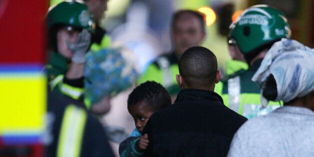 A child is brought to an ambulance within the security cordon as Grenfell Tower is engulfed by fire on June 14, 2017 in west London. The massive fire ripped through the 27-storey apartment block in west London in the early hours of Wednesday, trapping residents inside as 200 firefighters battled the blaze. Police and fire services attempted to evacuate the concrete block and said 'a number of people are being treated for a range of injuries', including at least two for smoke inhalation. / AFP PHOTO / Daniel LEAL-OLIVAS (Photo credit should read DANIEL LEAL-OLIVAS/AFP/Getty Images)