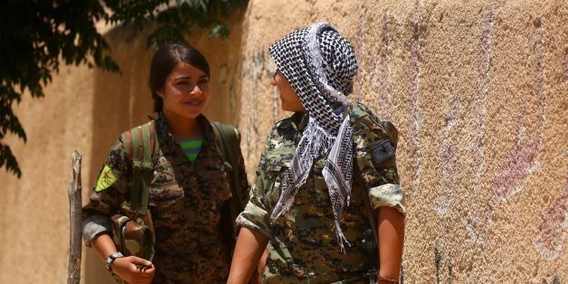 Members of the Syrian Democratic Forces (SDF), made up of an alliance of Kurdish and Arab fighters, chat as they walk in the western front of the Islamic State (IS) group's Syrian bastion of Raqa after seizing the area on June 11, 2017.US-backed Syrian fighters seized a second district of Raqa and launched a renewed assault on a base north of the city, as they pursued an offensive against the Islamic State group. / AFP PHOTO / DELIL SOULEIMAN (Photo credit should read DELIL SOULEIMAN/AFP/