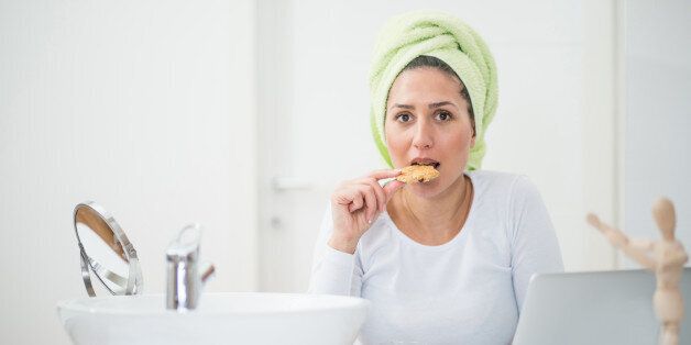 Woman eating cookie in the bathroom while doing a beauty treatment
