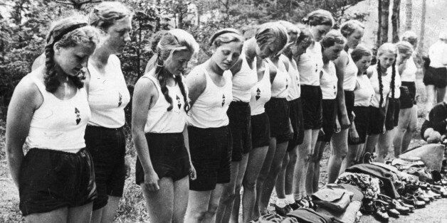June 1937: Young German women of the Hitler Youth Movement stand in line as they check their equipment at a vacation camp in the German Alps. They wear white tank-tops and shorts, and hold their hands behind their backs. (Photo by New York Times Co./Getty Images)