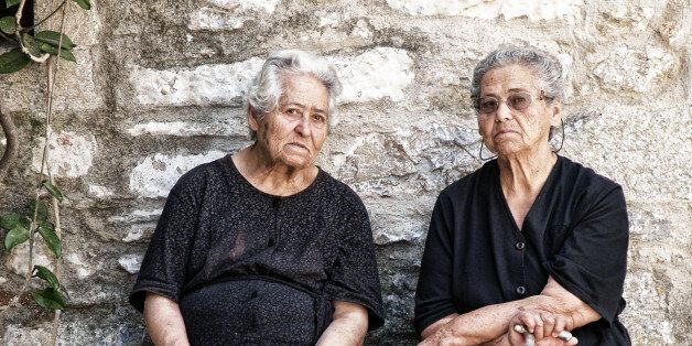 'Chios, Greece - August 18, 2008: Unidentified typical old ladies in Pirgi of Chios island gossiping and enjoying the afternoon sun outside a church in the central square of the village in Chios island, Greece'