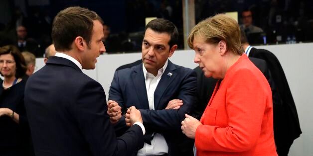 (L-R) France's President Emmanuel Macron, Greece's Prime Minister Alexis Tsipras and Germany's Chancellor Angela Merkel speak to one another during a working dinner meeting at the NATO (North Atlantic Treaty Organization) headquarters in Brussels on May 25, 2017 during a NATO summit. / AFP PHOTO / POOL / Matt Dunham (Photo credit should read MATT DUNHAM/AFP/Getty Images)
