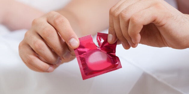 Horizontal view of male hands opening condom