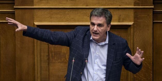 Greek Finance Minister Euclid Tsakalotos gives a speech during a parliamentary session in Athens on May 18, 2017. Greek police fired tear gas at a thousands-strong demonstration in Athens against new austerity cuts turned violent with some hooded youths throwing Molotov cocktails. The parliament is set to pass a bill in a vote expected around midnight which Athens hopes will help it gain a pledge of debt relief and loan disbursements by the country's EU-IMF creditors this month. / AFP PHOTO / An