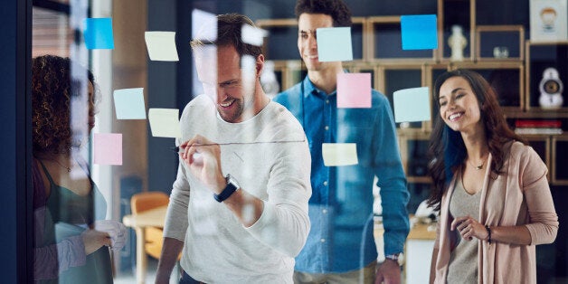 Cropped shot of a group of young designers brainstorming with notes on a glass wall in an office