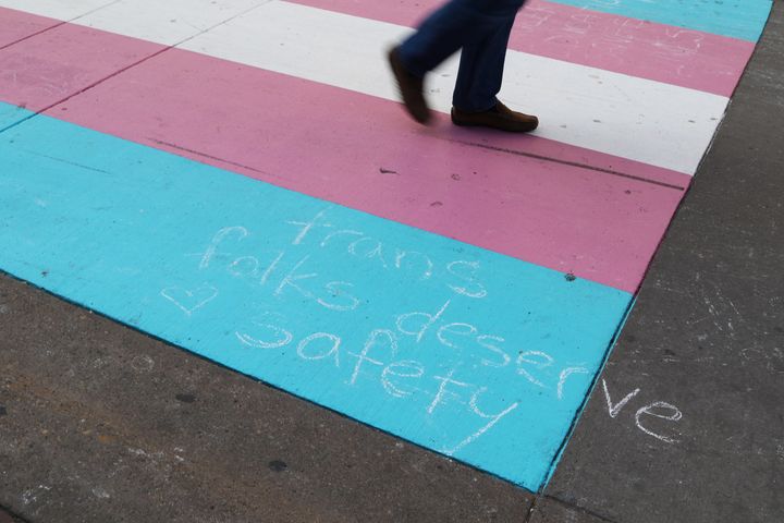 A person walks on a trans Pride flag crosswalk in Calgary on Sunday, Aug. 18, 2019.