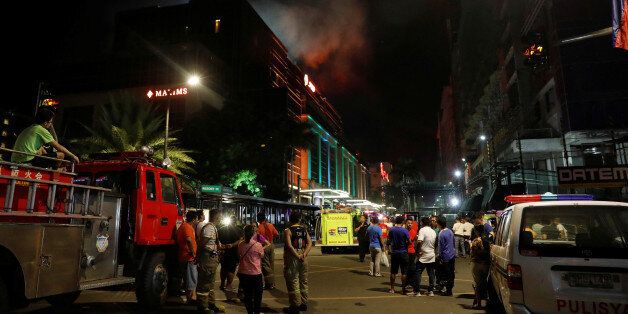 Evacuated employees and guests of hotels stand along a road and watch as smoke billows from a Resorts World building in Pasay City, Metro Manila, Philippines June 2, 2017. REUTERS/Erik De Castro TPX IMAGES OF THE DAY