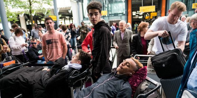LONDON, ENGLAND - MAY 28: People lie on their luggage as they queue outside Heathrow Airport Terminal 5 on May 28, 2017 in London, England. Thousands of passengers face a second day of travel disruption after a British Airways IT failure caused the airline to cancel most of its services. (Photo by Jack Taylor/Getty Images)
