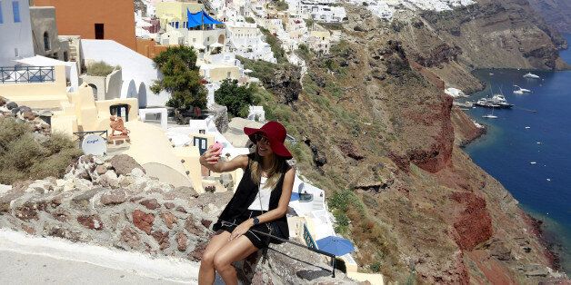 A tourist takes a selfie in the village of Oia on the Greek island of Santorini, Greece, July 1, 2015. REUTERS/Cathal McNaughton/Files