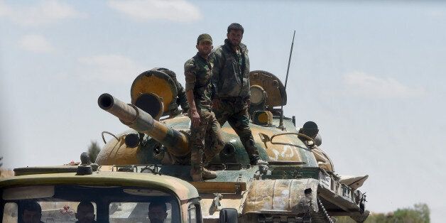 Syrian soldiers stand on a tank loaded on a lorry as they patrol their positions near the ancient city of Palmyra on May 5, 2016.Leading Russian musicians staged a classical concert in the ancient theatre of Syria's ravaged Palmyra in a show by the Kremlin to herald its successes in the war-torn country. / AFP / VASILY MAXIMOV (Photo credit should read VASILY MAXIMOV/AFP/Getty Images)