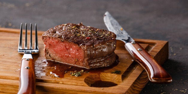 Filet Mignon Steak on wooden board on black background