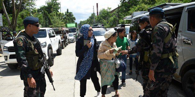 Philippine policemen check evacuees from Marawi aboard a van at a checkpoint by the entrance of Iligan City, in southern island of Mindanao on May 24, 2017.Philippine President Rodrigo Duterte warned that martial law would be 'harsh' and like a dictatorship, after imposing military rule in the south of the country to combat Islamist militants. / AFP PHOTO / TED ALJIBE (Photo credit should read TED ALJIBE/AFP/Getty Images)