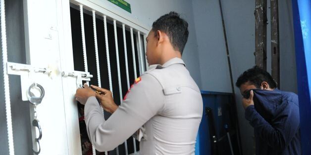 An Indonesian policeman escorts a man to a cell prior to his trial at a shariah court in Banda Aceh on May 17, 2017. A sharia court on May 17 sentenced two men to be publicly caned for gay sex for the first time in Indonesia's conservative province of Aceh, the latest sign of a backlash against homosexuals in the Muslim-majority country. / AFP PHOTO / CHAIDEER MAHYUDDIN (Photo credit should read CHAIDEER MAHYUDDIN/AFP/Getty Images)