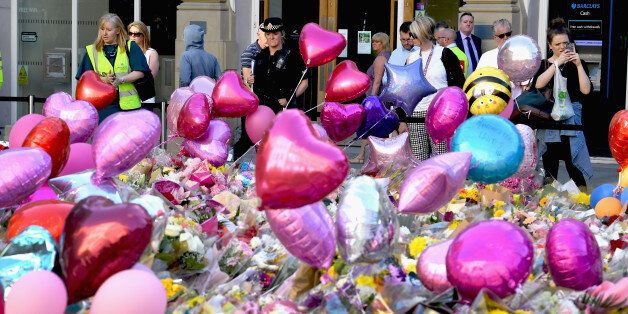MANCHESTER, ENGLAND - MAY 26: Members of the public look at tributes left for the people who died in Monday's terror attack at the Manchester Arena on May 26, 2017 in Manchester, England. An explosion occurred at Manchester Arena on the evening of May 22 as concert goers were leaving the venue after Ariana Grande had performed. Greater Manchester Police are treating the explosion as a terrorist attack and have confirmed 22 fatalities with many more injured. (Photo by Jeff J Mitchell/Getty Images)