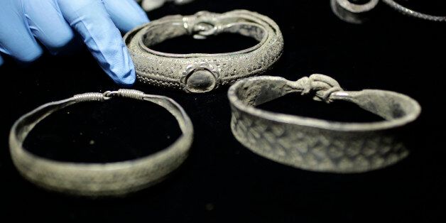 A museum assistant holds a Viking arm-ring at the British Museum in London December 14, 2011. The coins form part of the Silverdale Viking Hoard, which contains a total of 201 silver objects and a well preserved lead container, and was discovered in September 2011 with a metal-detector in the Silverdale area of North Lancashire. REUTERS/Stefan Wermuth (BRITAIN - Tags: ENTERTAINMENT SOCIETY)