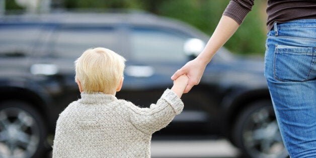 Mother and toddler son crossing the street on the crosswalk close up