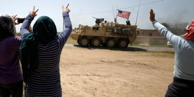 People gesture at a U.S military vehicle travelling in Amuda province, northern Syria April 29, 2017. Picture taken April 29, 2017. REUTERS/Rodi Said